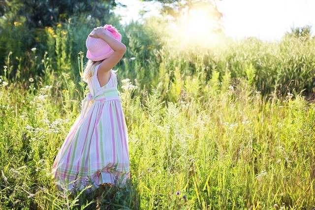 ילדה עם שמלה עומדת בשדה ירוק